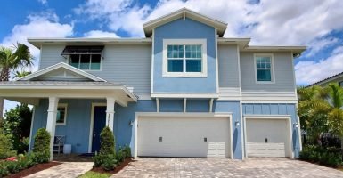 A blue coastal style home with a three car garage.
